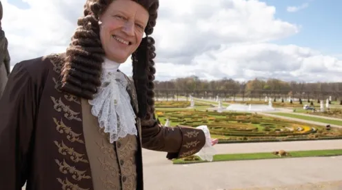 Mann mit Per&uuml;cke in Kleidung aus der Barockzeit in einem Barockgarten
